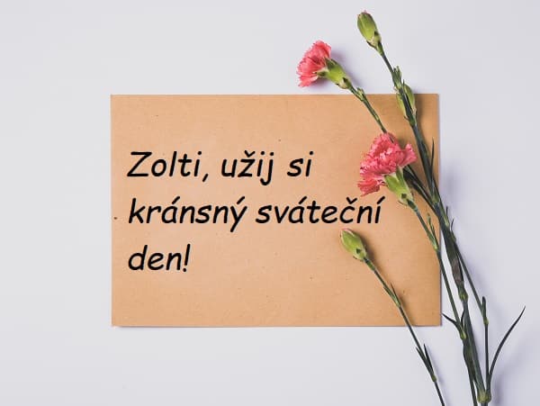 Papírová kartička s přáním k svátku Zoltánovi a čerstvými růžovými karafiáty.