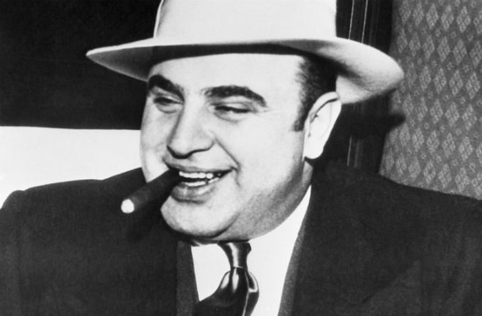 Černobílý snímek Al Caponeho s doutníkem.