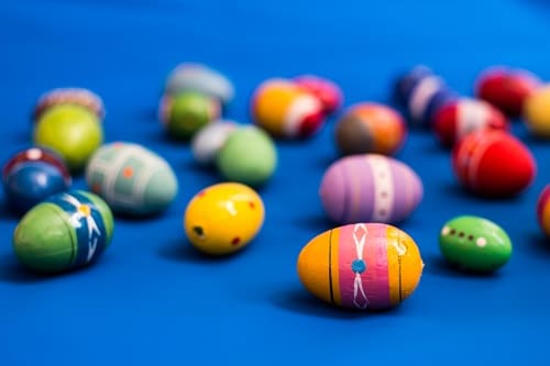 Modrý velikonoční MMS obrázek s rozházenými malovanými barevnými vajíčky. 