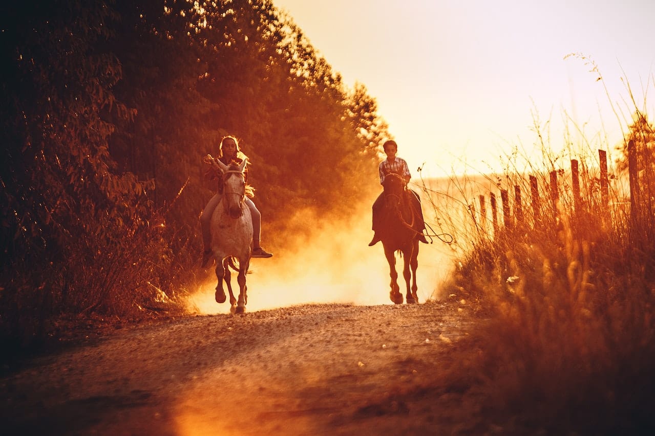 Děti na koních v západu slunce.