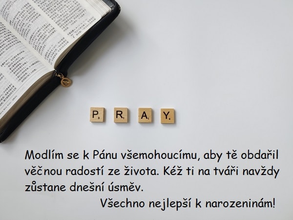 Křesťanské přání k narozeninám na pozadí bible s dřevěnými kostkami, které dohromady dávají nápis "Pray".
