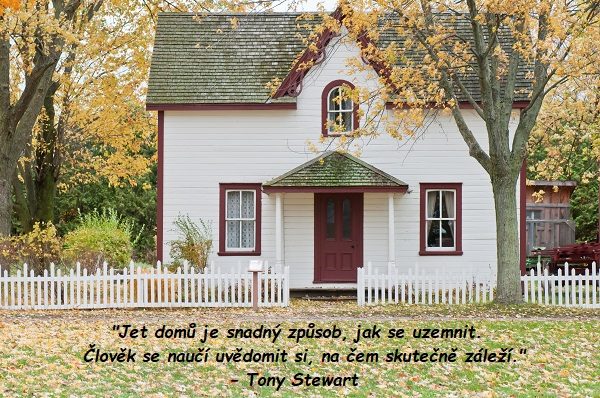 Bílý dům s bílým plotem v podzimní přírodě s domovským citátem od Tonyho Stewarta.
