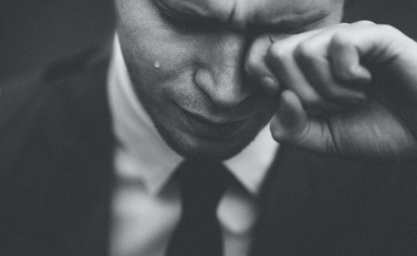 Černobílá fotografie plačícího muže v obleku