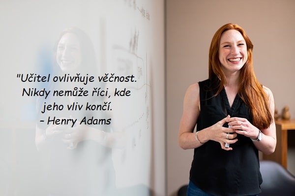 Smějící se žena před tabulí s citátem o učitelích od Henryho Adamse.