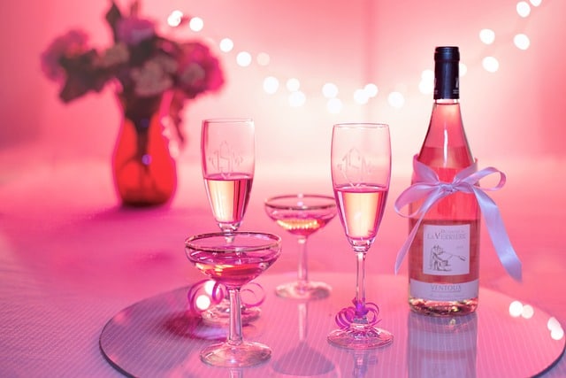 Sklenice s růžovým šampaňským s růžovými světýlky.