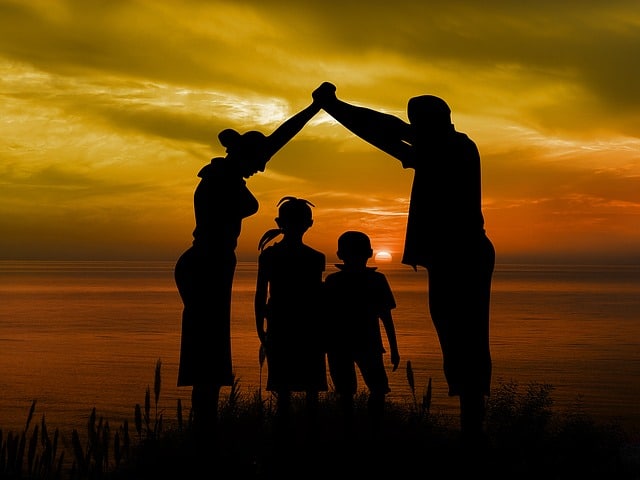Semknutá rodina u moře při západu slunce.