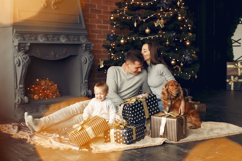 Rodina u vánočního stromku s malým dítětem a psem.