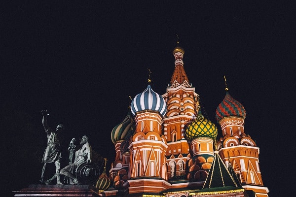 Domek v ruském stylu pod noční oblohou se sochami v popředí.