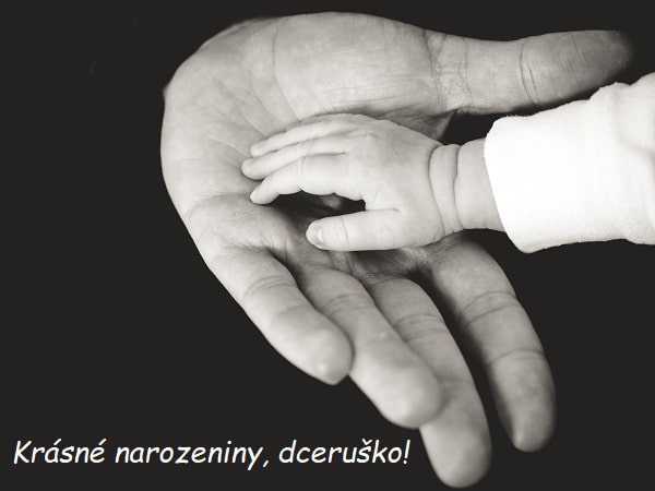 Černobílá fotografie s detailem na dospělou dlaň, na níž je položená ručka malého miminka s přáním dceři k narozeninám. 