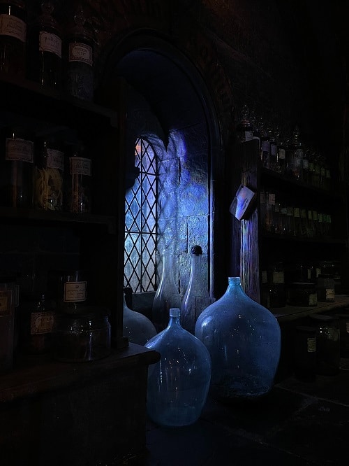 Přání k pálení čarodějnic s detailem na čarodějnické nádoby v tmavé komnatě s oknem.
