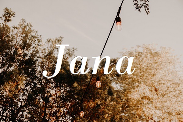 Jméno "Jana" na pozadí fotografie světelného řetězu ze žárovek a rozkvetlých stromů.