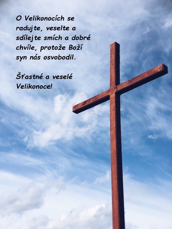 Hnědý dřevěný kříž s nebeským pozadím a blahopřáním ke krásnému prožití Velikonoc.