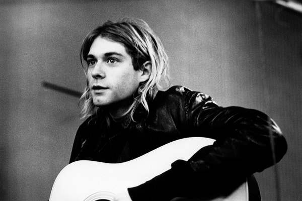 Kurt Cobain hrající na kytaru na černobílé fotografii