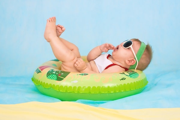 Přání k narození syna s malým miminkem v nafukovacím kruhu se slunečními brýlemi.