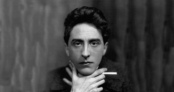 Černobílá fotografie mladého Jeana Cocteaua držícího cigaretu