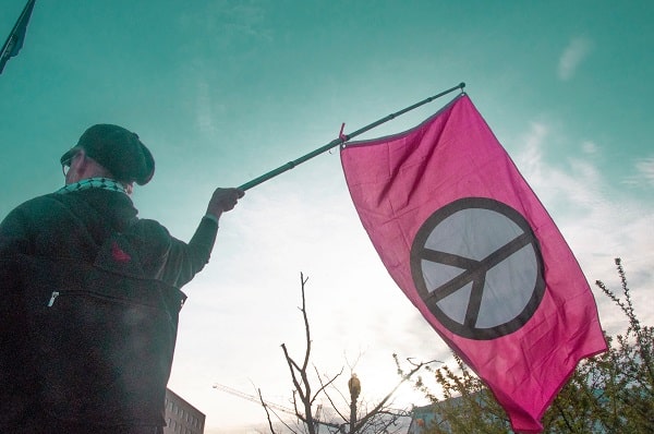 Muž v uniformě držící vlajku se symbolem míru
