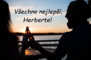 Muž se ženou připíjející si láhvemi piva při západu slunce, s nápisem Všechno nejlepší, Herberte!