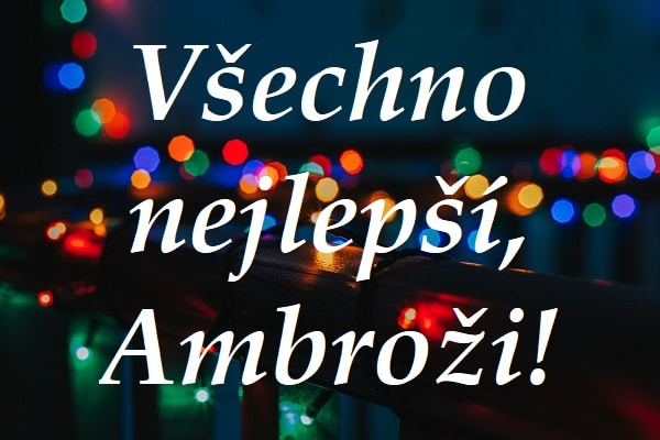 Nápis "Všechno nejlepší, Ambroži!" na pozadí zábradlí ozdobeném vánočními světýlky.