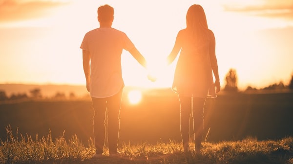 Pár držící se za ruku při západu slunce