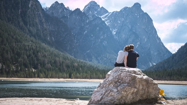 Pár sedící na kameni u horského jezera
