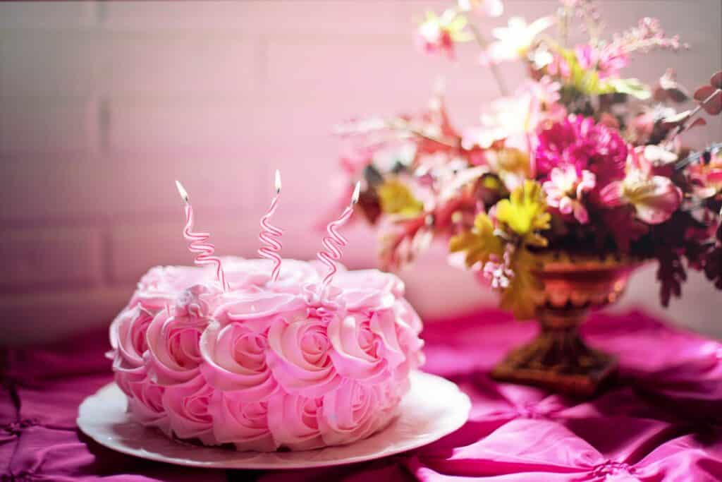 fotografie narozeninového dortu se svíčkami a květinami v pozadí