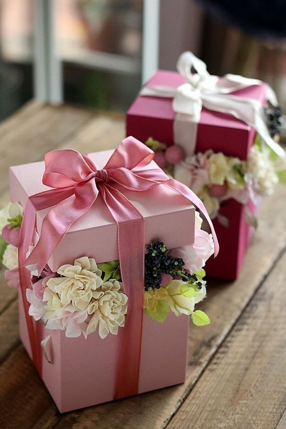 Růžové dárkové krabice k narozeninám s kytkami a růžovou stuhou. 