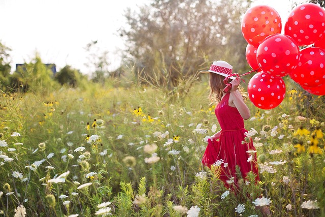 Přání k svátku s dívkou na louce držící balonky.