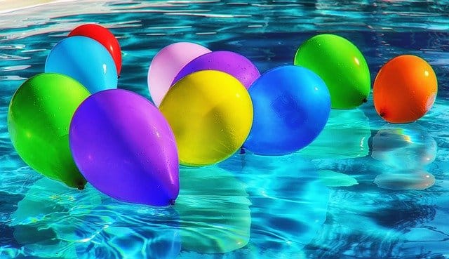 Přání k svátku s barevnými balony na vodě.