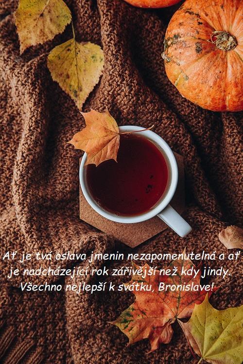 Přání k svátku Bronislavovi na pozadí hrníčku s čajem na dece, zdobené podzimním listím.
