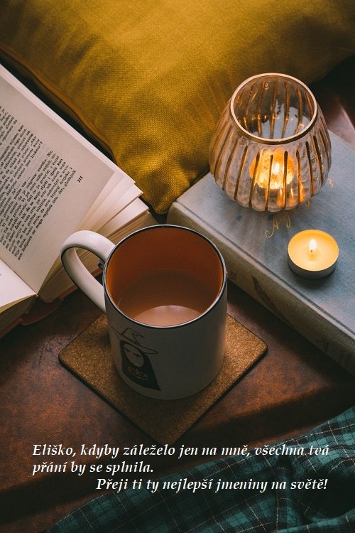 Šálek kávy se svíčkou, knihou a přáním všeho nejlepšího ke jmeninám Elišce.