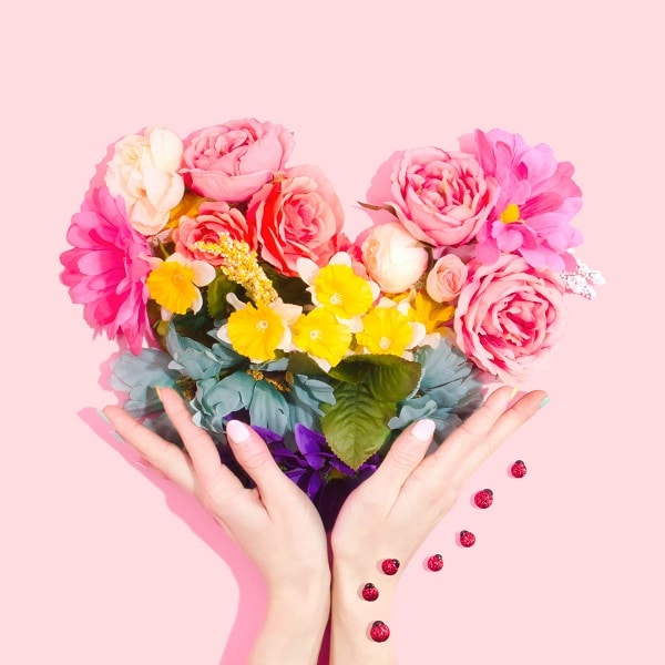 Ruce držící srdce z květů.