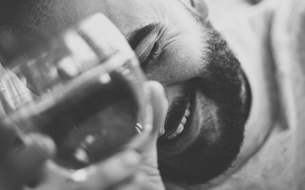 Detail na tvář smějícího se muže se sklenkou vína v ruce