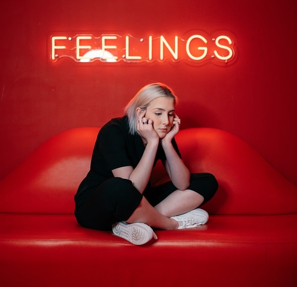 Smutná dívka sedící pod nápisem Feelings