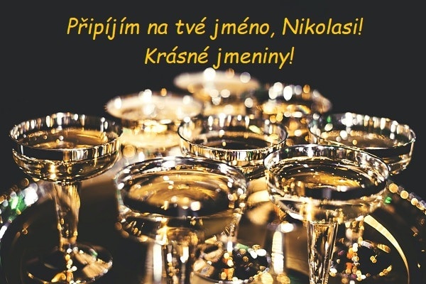 Tác se sklenicemi šampaňského a s přáním krásných jmenin Nikolasovi na černém pozadí.