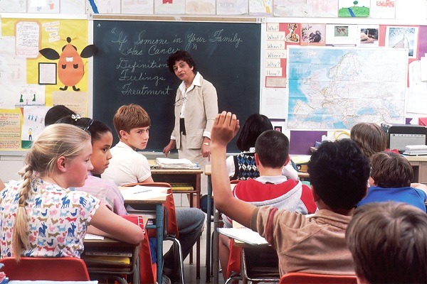 Třída žáků na základní škole s paní učitelkou stojící u tabule.