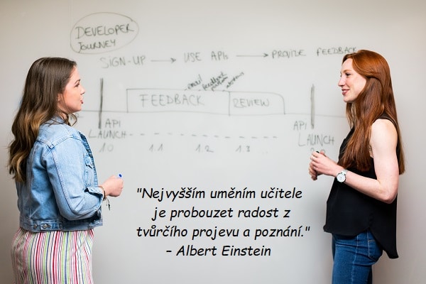 Citát pro učitele od Alberta Einsteina na pozadí fotografie dvou žen debatujících před tabulí.