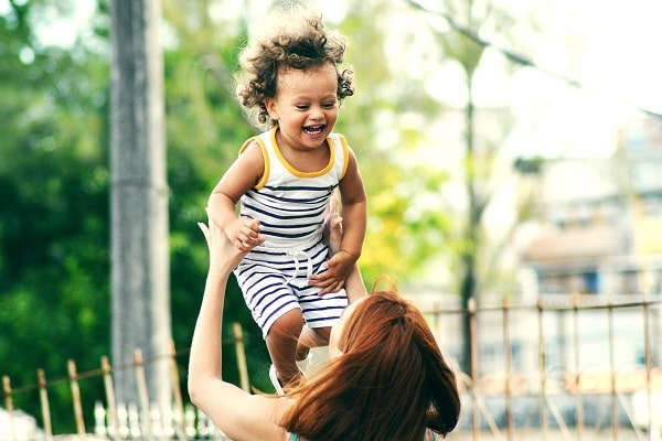 Žena vyhazující smějící se dítě do vzduchu