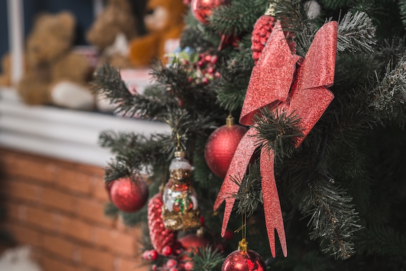 Vánoční červená mašle na ozdobeném stromku, vánoční atmosféra.