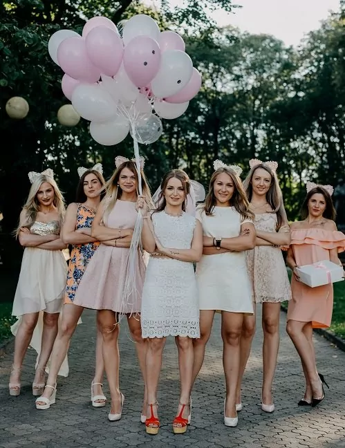 Skupina dívek na rozlučce se svobodou, s nevěstou, držící nafukovací balónky.